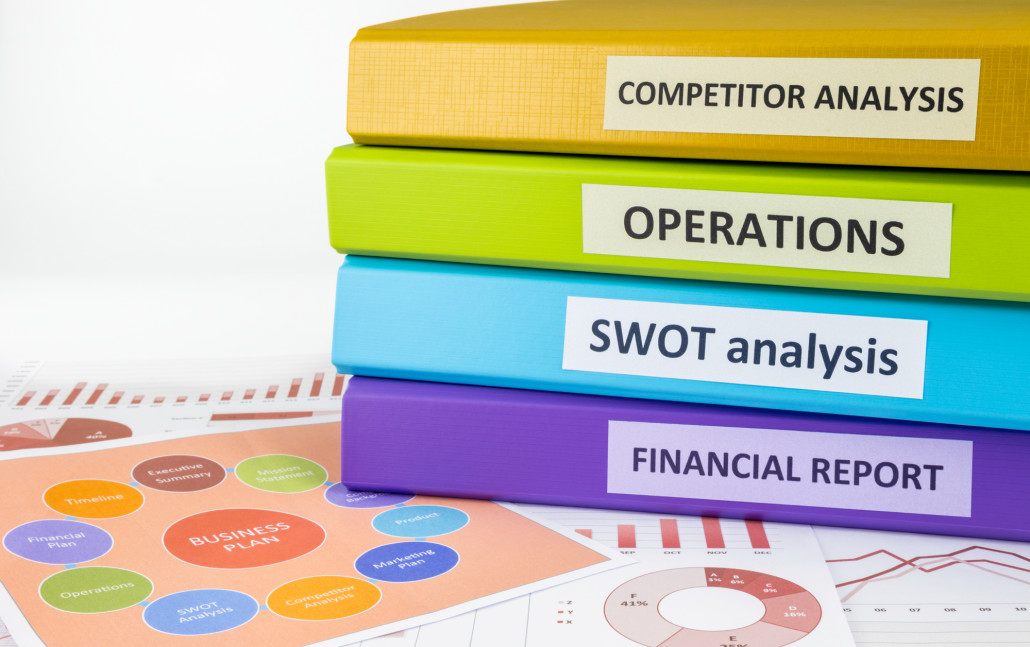 Colorful document binders: SWOT, competitor analysis, operation and financial report place on graph analysis and business plan chart, concept to business plan management